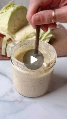 a person dipping something into a jar with a spoon