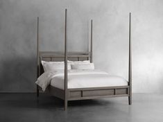 a bed with four posts and white linens in a room that is painted gray