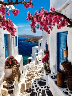 an alley way with blue doors and pink flowers on the trees in front of it