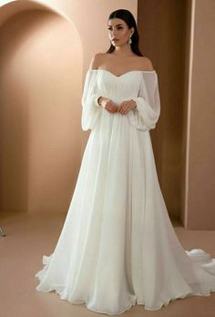 a woman in a white wedding dress with long sleeves