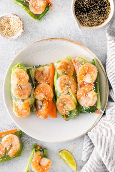 shrimp and avocado spring rolls on a plate with dipping sauce next to them