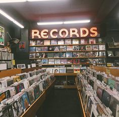 a record store with records on the shelves and neon sign in the background that reads records