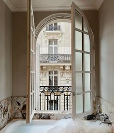 an open window with a view of a bathtub in front of a balcony and balconies