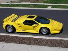 a yellow sports car is parked on the side of the road in front of a curb