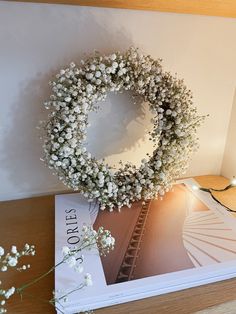 a white wreath on top of a book next to flowers