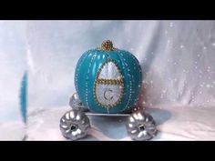 a small blue pumpkin sitting on top of a metal stand with silver balls around it