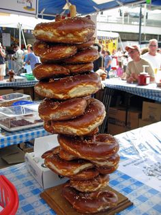 a stack of doughnuts sitting on top of a wooden board in front of people