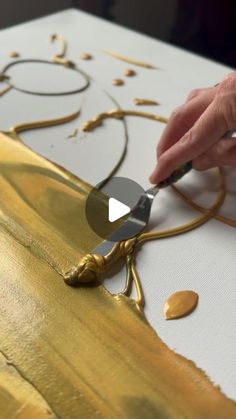 a person is painting gold on a white surface