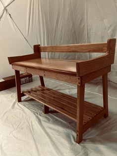 a wooden bench sitting on top of a white sheeted floor next to a book shelf