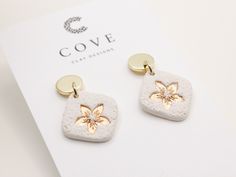 a pair of white and gold earrings on top of a piece of paper with the words cove