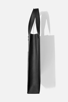 Our take on a classic piece, boasting sturdy construction and clean lines. Handcrafted in Montreal from our signature matte black pebbled cowhide, Tote is an everyday carryall with a flexible body and structured base. Its main compartment can fit up to a 16-inch laptop. Large exterior and small interior pockets are integrated for everyday essentials. + Width: 12.5in / 32 cm+ Height: 16.5in / 41 cm+ Depth: 3.5in / 9 cm+ Handle Drop: 9.5in / 24 cm Leather Bag Pattern, Minimal Classic, Oversized Tote, Convertible Bags, Fashion Aesthetics, Black Pebbles, Montreal Canada, Purse Pouch, Mini Crossbody