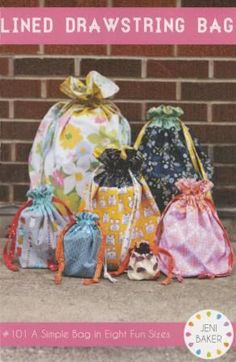 three drawstring bags sitting next to each other on the ground in front of a brick wall