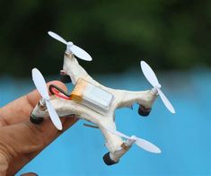 a hand holding a small white toy with propellers on it's side and an electronic battery attached to the blade