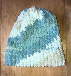 a blue and white knitted hat sitting on top of a wooden floor