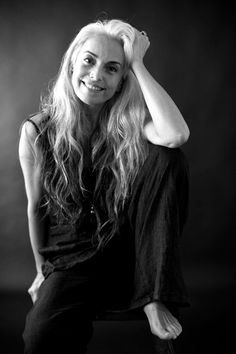 a black and white photo of a woman with long blonde hair sitting on a chair