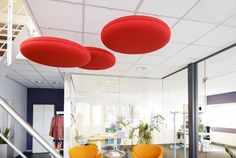 three red chairs are sitting in front of a glass wall and some stairs leading up to the second floor