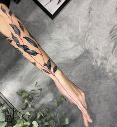 a woman's arm with leaves on it and a red line going through the leg