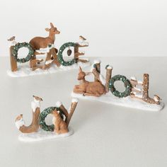 three small deer figurines sitting on top of snow covered letters that spell out the word joy