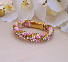 a close up of a bracelet on a table with flowers in the backgroud