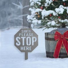 a small christmas tree sitting next to a wooden barrel with a red bow on it