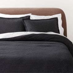 a bed with black and white sheets and pillows