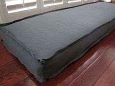 a large gray bed sitting on top of a hard wood floor next to a door