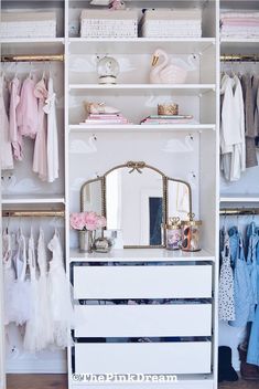 a white dresser sitting next to a closet filled with clothes