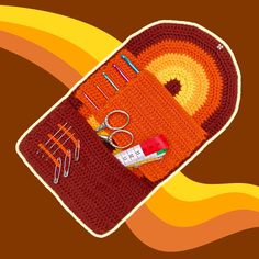 an orange crocheted case with scissors and other crafting supplies on top of it