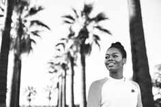 a black and white photo of a woman smiling with palm trees in the back ground