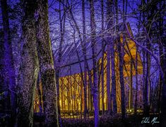 a house in the woods lit up at night with purple light coming from its windows