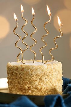 a cake with five candles on it sitting on a plate next to a blue cloth