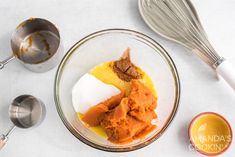 the ingredients to make an orange cake are in a bowl next to measuring spoons