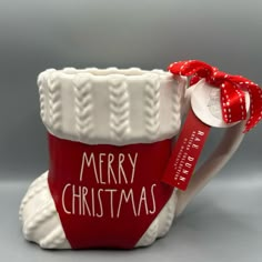 a red and white ceramic mug with a merry christmas tag on it's side