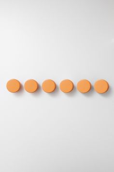 five orange circles lined up in a row on a white surface with one red dot at the end