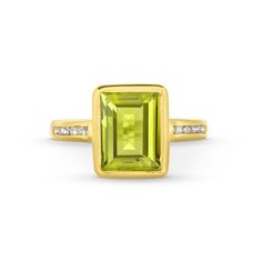 This Peridot Diamond Bezel Ring features an emerald cut peridot gemstone totaling approximately 3 carats, accented by a line of brilliant round diamonds on each side. Classic Green Emerald Ring With Gemstone Accents, Green Octagon Diamond Ring, Emerald Cut Green Gemstones With Accent Stones, Classic Green Gemstones With Accents, Green Diamond Ring With Gemstone Accents For May Birthstone, Fine Jewelry Green Diamond Ring With Gemstone Accents, Luxury Green Channel Set Rings, Classic Peridot Gemstone Diamond Ring, Green Peridot Diamond Ring With Accent Stones