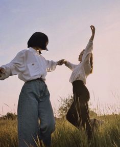 two people standing in tall grass holding hands