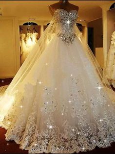 a white wedding dress on display in a room with mannequins and lights