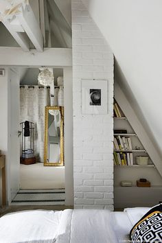 an attic bedroom with white brick walls and exposed ceiling