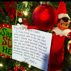 an elf is holding a letter to santa on the christmas tree with ornaments around him