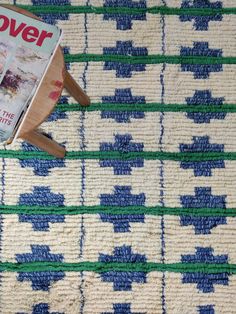 a wooden paddle laying on top of a blue and white rug next to a magazine