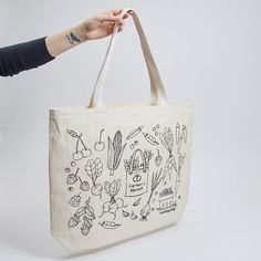 We made a bag with our friends at Winter Water Factory! Cut, Sewn and Printed down the street from us in Winter Water Factory's local Brooklyn studio, this fun oversized tote features illustrations of our new fruit and veggie ornaments. Check out more from Winter Water Factory here. Made locally in Brooklyn with up-cycled cotton canvas. Features black line illustrations of our Farmer's Tote Bag Ornament, Pick Your Own Blueberry Basket, Strawberries, Cherries, Beaded Peapod, Carrot, Radish, Garli Organic Tote Bag For Shopping, Organic Style Tote Bag For Shopping, Basket Strawberries, Blueberry Basket, Garlic Corn, Farmers Market Tote Bag, Water Factory, Line Illustrations, Fruit And Veggie