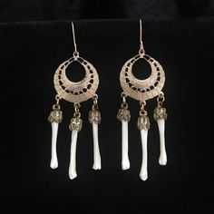 Real muskrat foot bones are 1 inch and are held by antiqued brass caps. They hang from .75 inch, Victorian style, etched brass components. The earrings are dangling from contemporary gold filled French hook earrings. The earrings as a whole measure 2.75 inches. They are very light weight and comfortable. The vintage, circa 1960, etched brass hoops and brass caps are from old stock , never used. They have contemporary bones added to them. The detail in the cast earrings include open work design a Bohemian Bone-colored Nickel-free Earrings, Bone Colored Metal Earrings For Pierced Ears, Bohemian Bone-colored Pierced Earrings, Bohemian Bone-colored Earrings, Hand-cast Brass Dangle Earrings, Unique Bone-colored Nickel-free Earrings, Nickel-free Bone Dangle Earrings, Nickel-free Bone-colored Dangle Earrings, Hand Cast Brass Dangle Jewelry