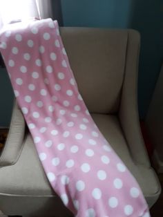 a pink and white polka dot blanket sitting on top of a chair