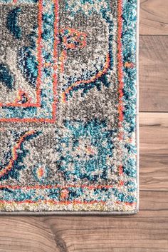 an area rug with blue, orange and white colors on wood flooring next to a plant