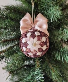 an ornament hanging from a christmas tree with pink ribbon and bow on it