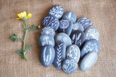 some rocks with flowers painted on them next to a yellow flower and burlock