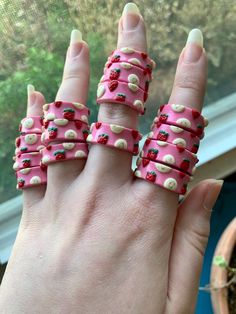 a woman's hand with five rings made out of doughnuts and strawberries