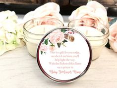 two small jars filled with flowers on top of a wooden table next to white roses