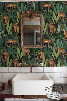 a bathroom sink sitting under a mirror next to a green wallpaper covered in giraffes