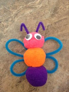 a colorful toy sitting on top of a stone floor next to a ball and pair of scissors